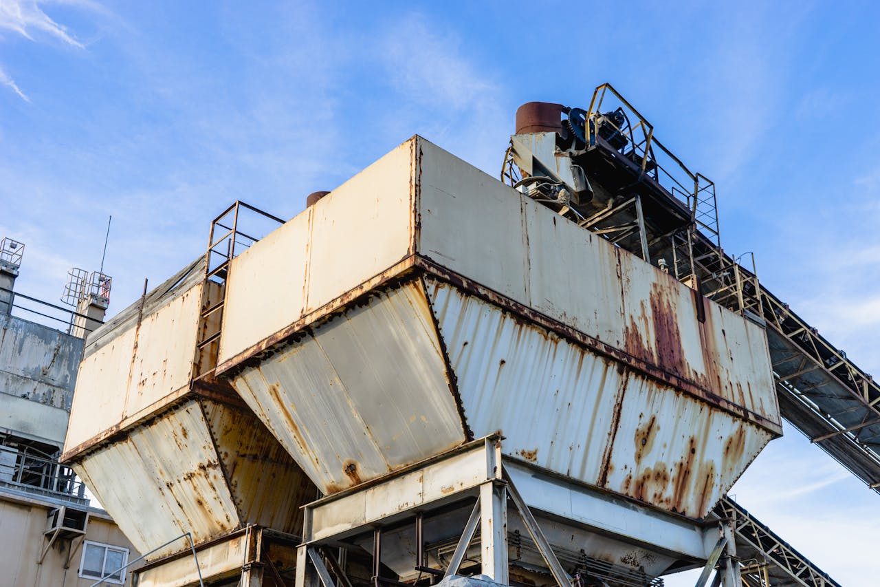 Close-up of rusty industrial equipment against a clear blue sky.
